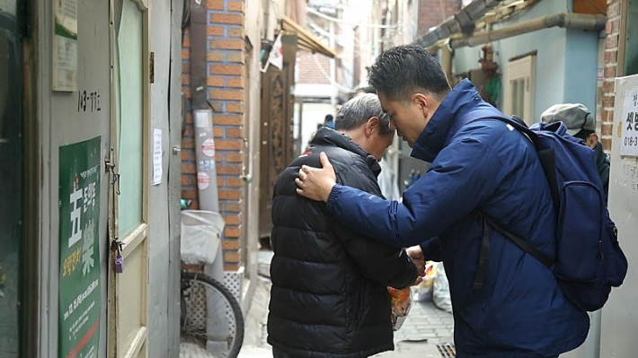 쪽방촌에서 살아가는 주민에게 간식을 드리고 교제 후 기도하는 손은식 목사. 본인 제공. 