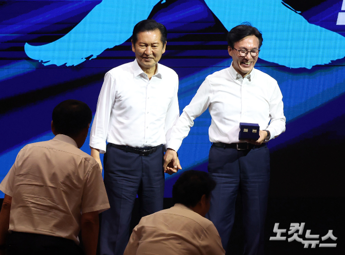 더불어민주당 김민석 대표가 27일 인천 영종구 인스파이어호텔에서 열린 정기국회 대비 국회의원 워크숍에 참석해 정청래 전 대표에게 감사패 전달 전 손을 맞잡고 있다. 인천=황진환 기자